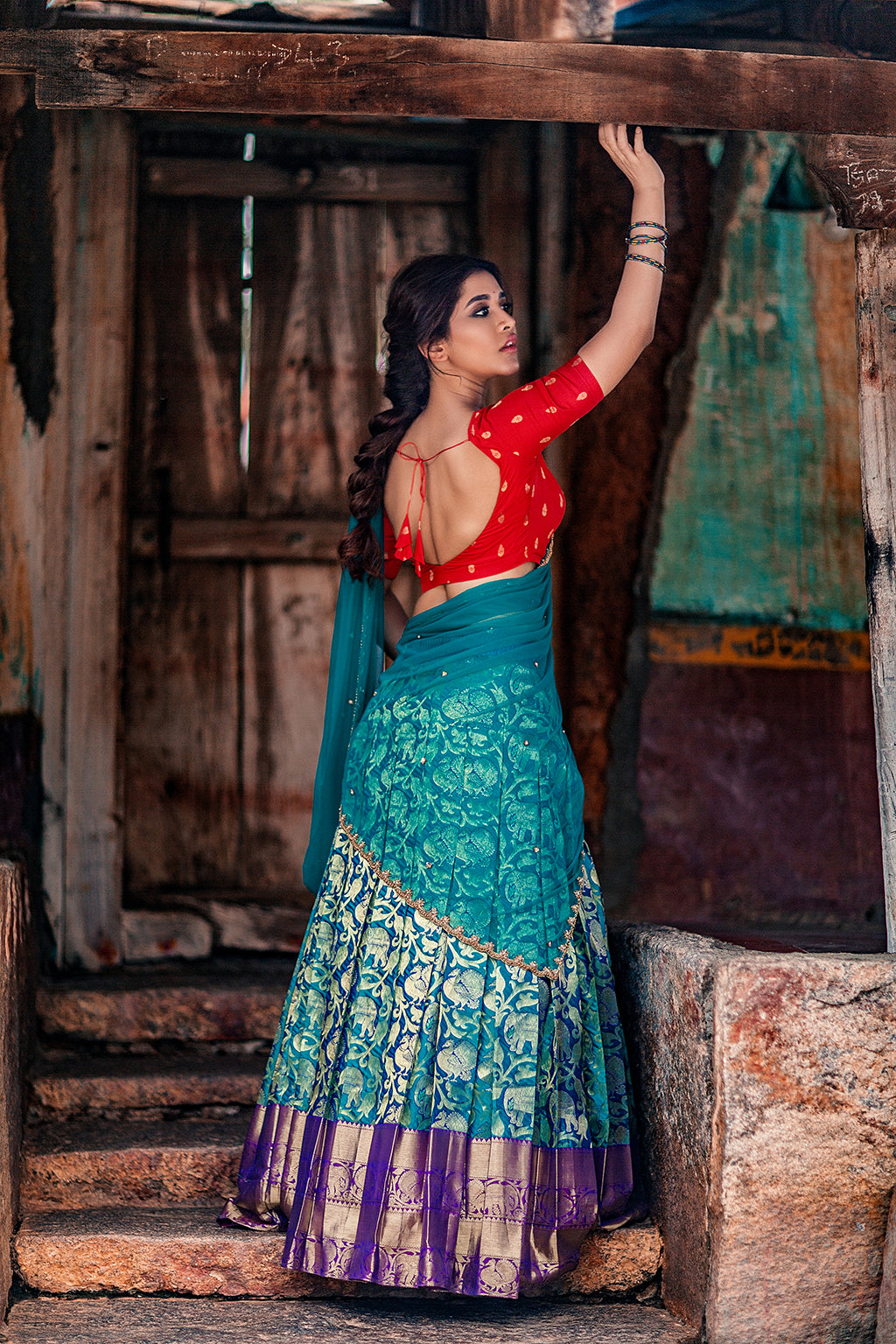 Sweetheart neck red brocade silk blouse with blue knife pleat kanchi silk skirt and blue tulle dupatta