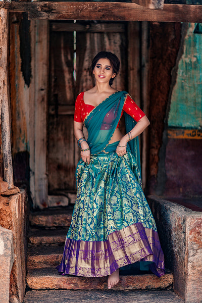 Sweetheart neck red brocade silk blouse with blue knife pleat kanchi silk skirt and blue tulle dupatta